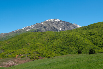 Naklejka premium Green plains, snowy mountains. Blue sky and snowy mountains. Snowy mountains of Tunceli. Pülümür Valley, Buyer Mountain, Sarıgül Plateau, Buyer Waterfall.Munzur, Tunceli, Türkiye. 