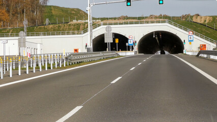 Entrance road tunnel on the express road. tunnel through the mountain. empty highway, green traffic...