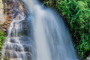 Natural background of waterfall flowing from high place through rocks and rainforest, the water flows in various ways according to the strength and beauty of the natural system.