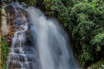 Natural background of waterfall flowing from high place through rocks and rainforest, the water flows in various ways according to the strength and beauty of the natural system.