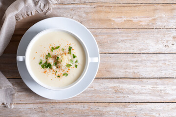 Cauliflower soup in bowl on wooden table. Top view. Copy space