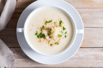 Cauliflower soup in bowl on wooden table. Top view
