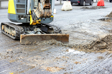 Excavator working on a busy urban road construction site during daylight hours