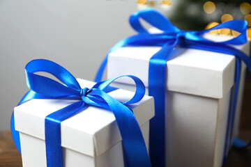 Beautiful gift box on the table with shining bokeh and Christmas tree behind