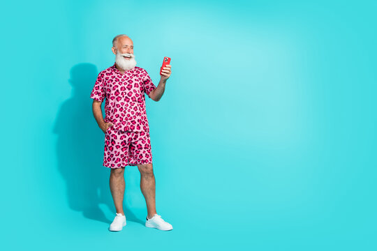 Full size photo of cool retired bearded male hold telephone wear trendy pink leopard print outfit isolated on aquamarine color background