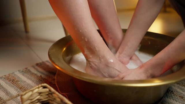 close up vertical video foot washing procedure in massage parlor wicker mat iron bowl with soap solution basket with scrub and towel feet of a young girl masseur washes feet