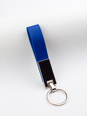 Close up of minimalist leather blue keychain with metal fittings on white background