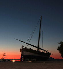 Naklejka premium Old sailing ship on shore at sunset. Dramatic scene. Background for design. Tourism and recreation. Sister Levante in Liguria. 