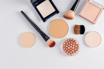 a set of cosmetic decorative makeup products in various packages and several brushes for applying makeup. white background. top view. beauty concept