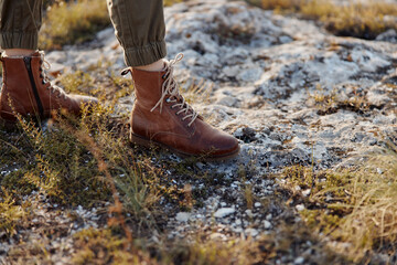 Person standing in the middle of a field wearing a pair of brown leather boots lonely wanderer in brown leather boots in the wide open field