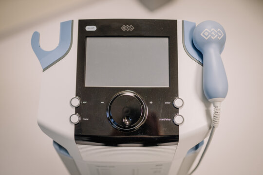 A close-up of a therapeutic medical device with a control screen and handheld applicator, commonly used in physical therapy and rehabilitation settings..
