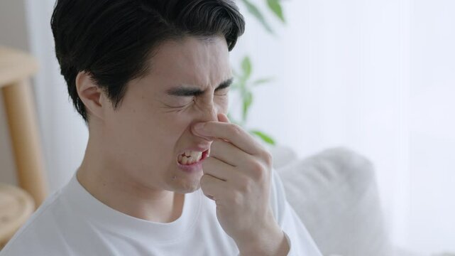 臭いに鼻をつまむ男性