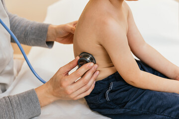 Doctor examining child's lungs with stethoscope during checkup