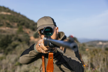 Hunter aiming with rifle scope in nature