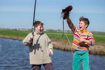 Funny fishing. Two of the boy's friends hooked an old shoe with a fishing rod and are laughing.