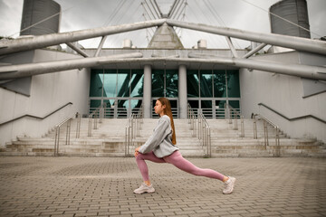 Young slender girl is doing yoga against the background of a building with steps