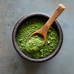 Close up of freshly ground bright green matcha tea powder in a rustic wooden bowl with a wooden spoon