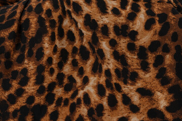 Background made of fabric with a leopard pattern. The cloth is brown with black animal spots.