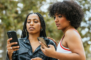 Two girls using smartphones outdoors in a park