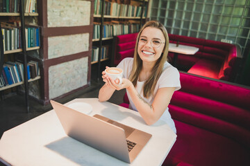 Photo of attractive blonde woman tasty coffee netbook wear white t-shirt working comfortable modern business center cafe interior indoors