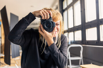 Photographer taking pictures in professional studio with photo equipment