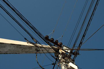 Bottom view of a electric pole with wires against blue sky	