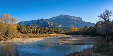 This image captures a beautiful autumn landscape with a winding river flowing gently through a forested valley. In the background