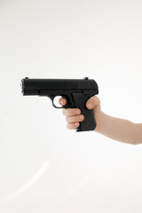 Close up male hand holding black plastic toy gun on white background.toy gun in hand ON A WHITE BACKGROUND