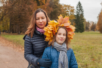 Cheerful woman with little daughter in Autumn park. Autumn walk