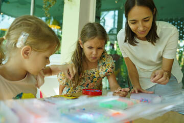 Teacher in workshop teched two girls how to assemble a thermo mosaic 