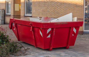 red open steel industrial waste container with construction waste