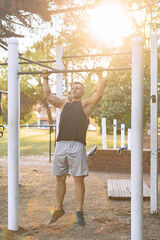 Obraz premium sports man pulls himself up on the horizontal bar, training in city during the summer, an active lifestyle, modern fitness workout.