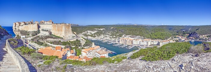 Historic Bonifacio on Corsica’s dramatic limestone cliffs against a clear blue Mediterranean sea...