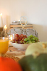 Pumpkins, various food and drinks, fall decorations, books and candles on the table. Fall hygge at home. Selective focus.
