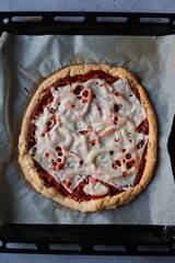 Pizza z sosem pomidorowym i serem krojona na blasze z papierem do pieczenia z nożem do pizzy
