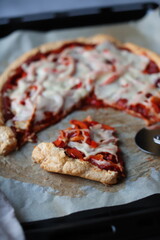 Pizza z sosem pomidorowym i serem krojona na blasze z papierem do pieczenia z nożem do pizzy