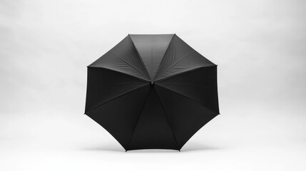 A black umbrella stands open against a clean white background, showcasing its sleek design and structure for potential advertising or product display