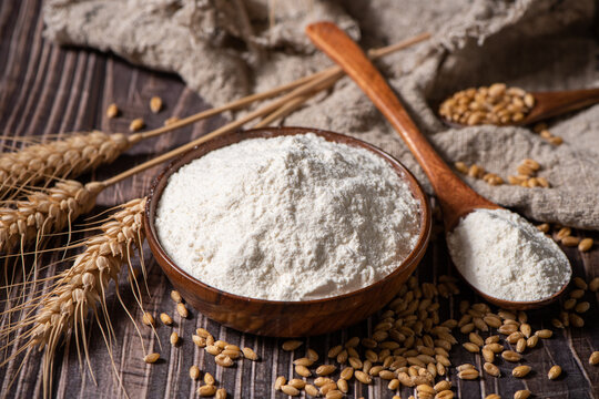 wheat flour and wheat ears on wooden table