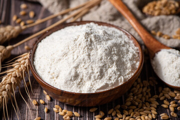 wheat flour and wheat ears on wooden table
