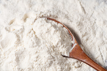 Close-up of white flour and wooden spoon background.