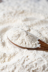 Close-up of white flour and wooden spoon background.
