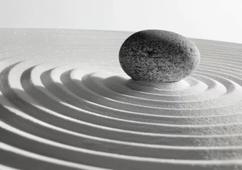 Papier peint photo Beige Zen garden with smooth white sand and circular raked patterns, closeup of grey stone in the center, soft focus background  © Veronika