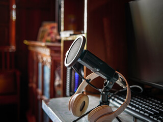 Podcast microphone resting on a desk in a recording ready podcasting home studio. Selective focus...