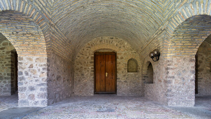 Obraz premium The Upper Caravanserai courtyard in Shaki, Azerbaijan, boasts magnificent stone walls and an arched ceiling, showcasing the area's rich architectural heritage.
