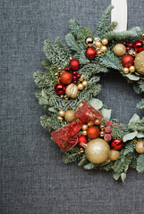 Christmas wreath decorated in gold and red colors on a gray background