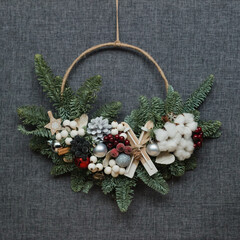 Christmas wreath decorated with cotton and dried flowers on a gray background