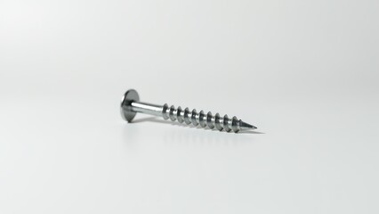 Screws and bolts for furniture repair. A single metallic screw lies on a clean, white surface, showcasing its shiny, threaded body and slotted head.