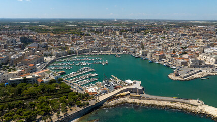 Obraz premium Aerial view of the port of the city of Trani, in Puglia, Italy. It is a small tourist seaport on the Adriatic Sea. There are many boats anchored in the clean water of the harbour.