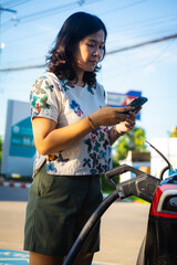 Woman use smartphone to charge EV car outdoor station travel trip
