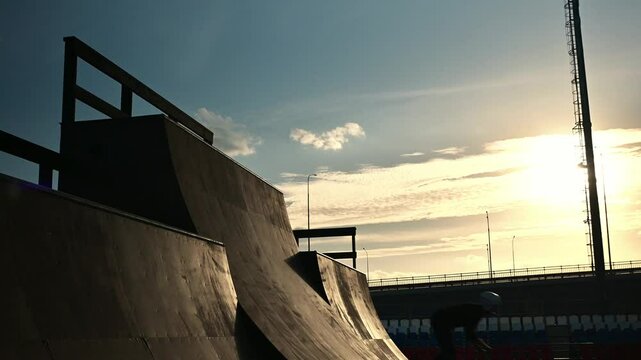 An athlete at a ski jumping competition . A cyclist on a BMX bike performs stunts at sunset. A stuntman rides in a skatepark and gets an adrenaline rush